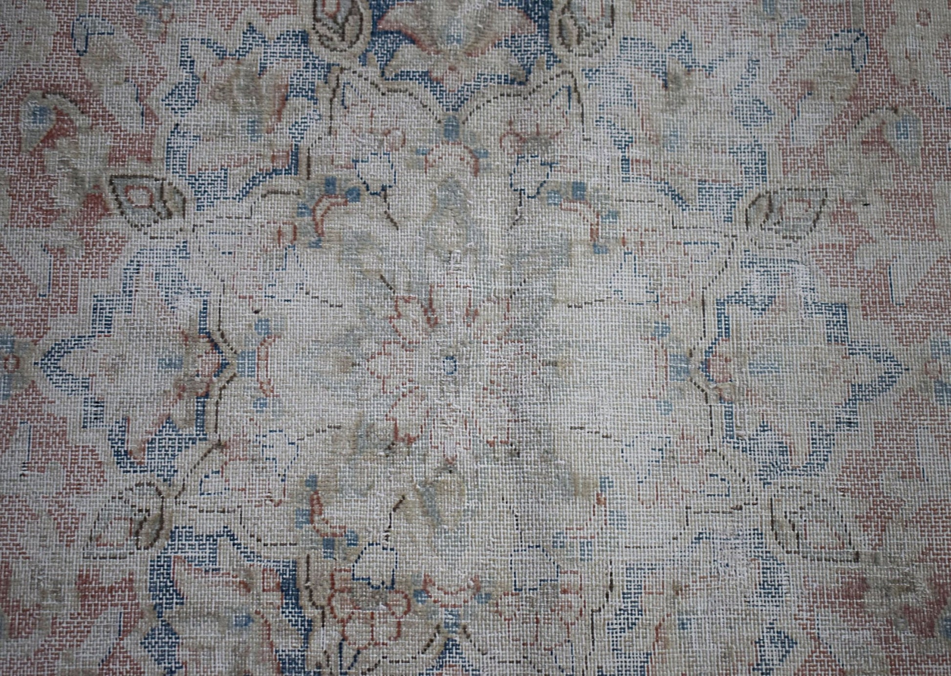 A vintage Persian Kerman rug featuring a faded floral medallion design in blue and muted red tones.