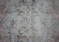 A vintage Persian Kerman rug featuring a faded floral medallion design in blue and muted red tones.