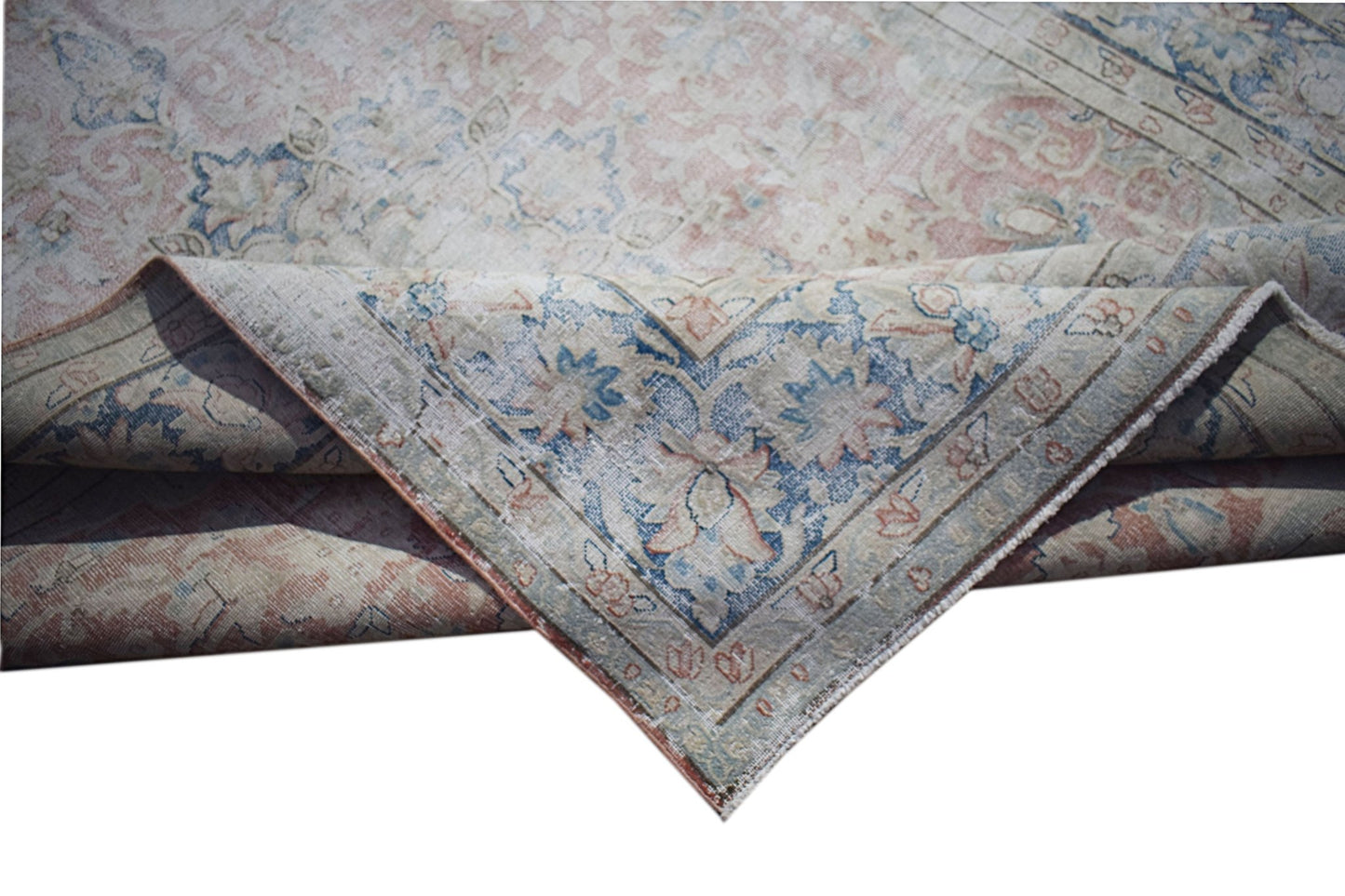 A vintage Persian Kerman rug featuring a faded floral medallion pattern in blue and soft pink.