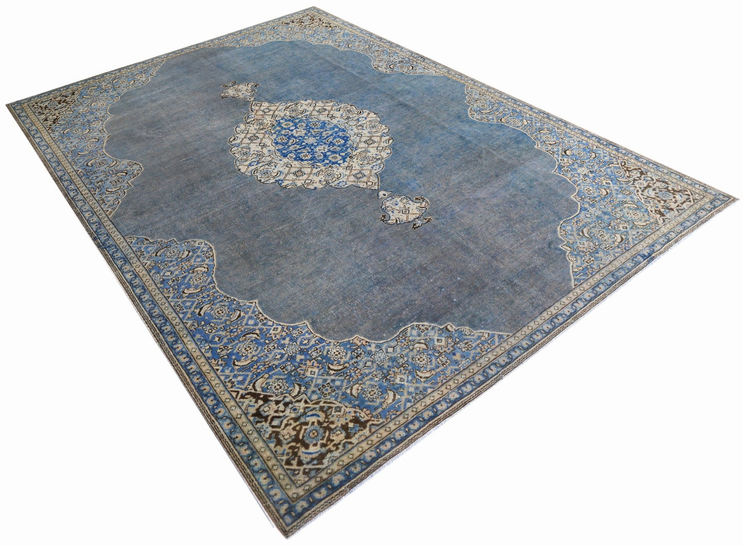 A vintage Persian Kerman rug featuring a central medallion and intricate floral patterns in blue.