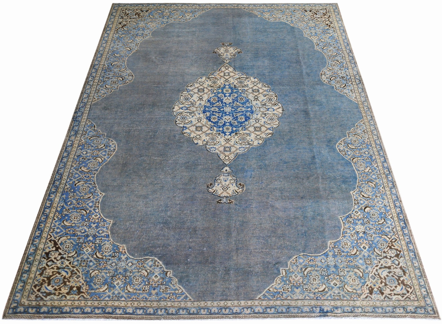 A vintage Persian Kerman rug featuring a central floral medallion on a blue field.