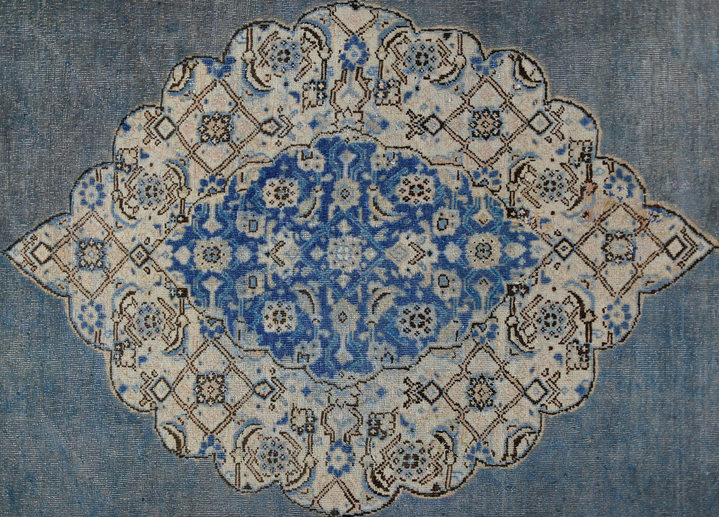A vintage Persian Kerman rug featuring an intricate blue and cream floral medallion design.