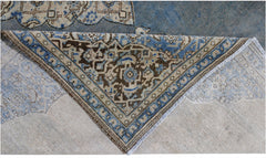 A corner of a vintage Persian Kerman rug is folded back to reveal its intricate floral pattern.