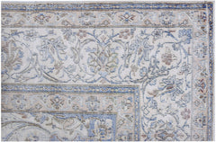 A close-up of a vintage Persian Kerman rug featuring intricate floral patterns in blue and beige.