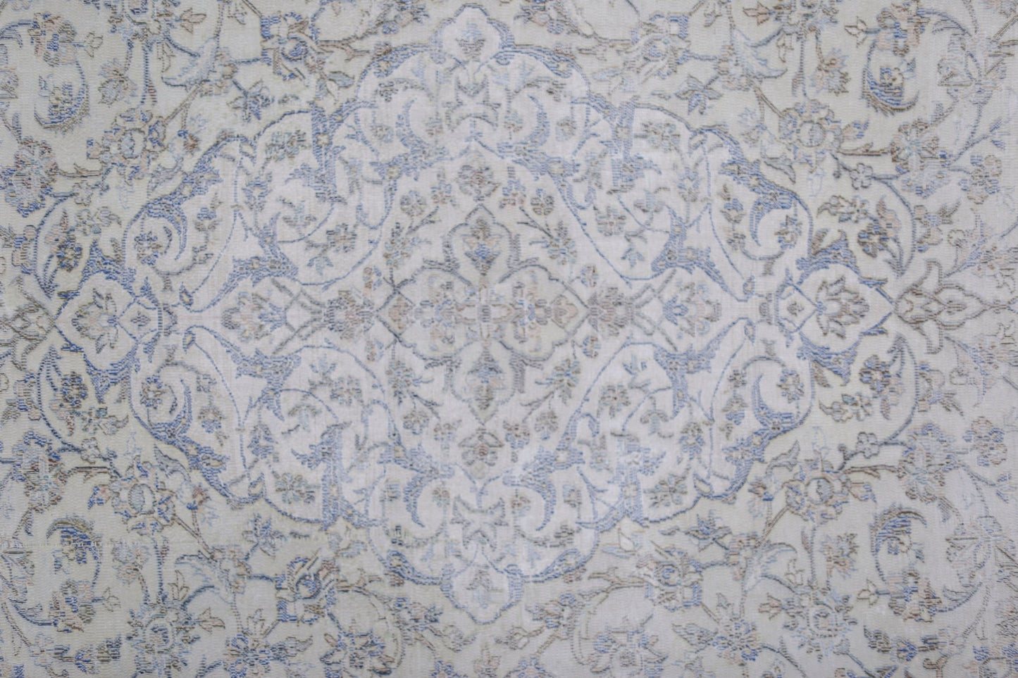 A vintage Persian Kerman rug featuring a central floral medallion in soft blue and beige tones.