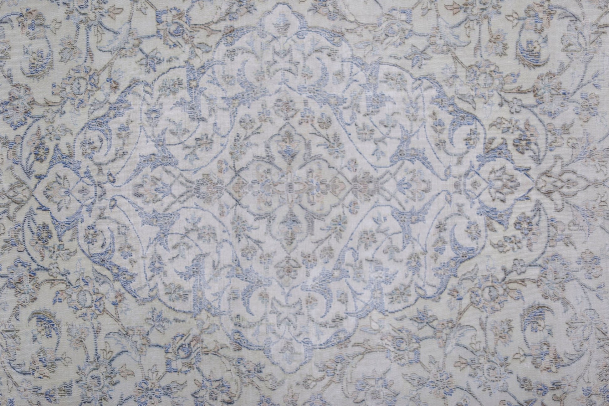 A vintage Persian Kerman rug featuring a central floral medallion in soft blue and beige tones.