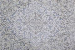 A vintage Persian Kerman rug featuring a central floral medallion in soft blue and beige tones.