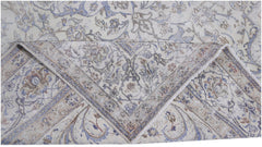 A vintage Persian Kerman rug featuring an intricate floral pattern in blue and beige tones.