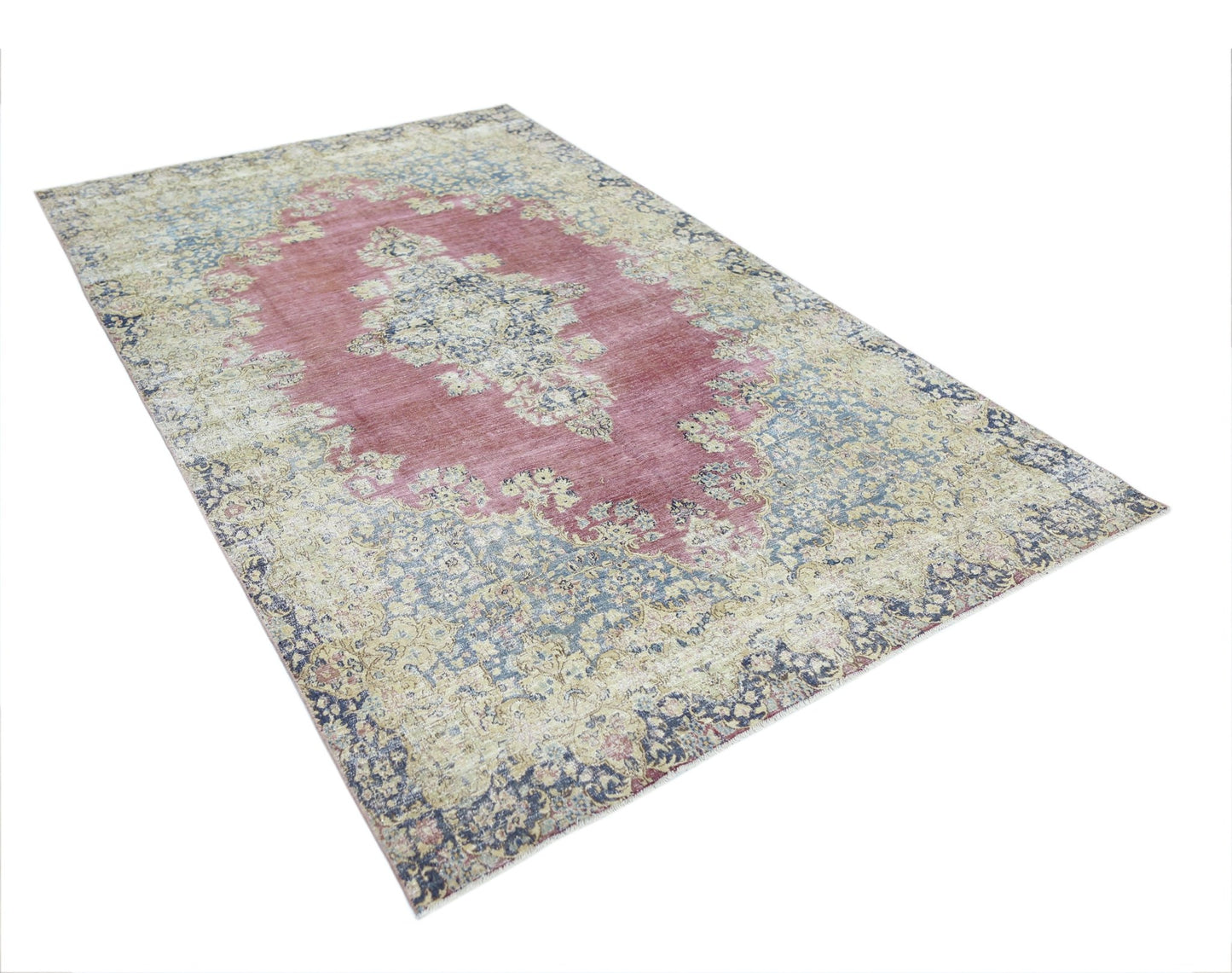 A vintage Persian Kerman rug featuring a central medallion and intricate floral patterns in pink.