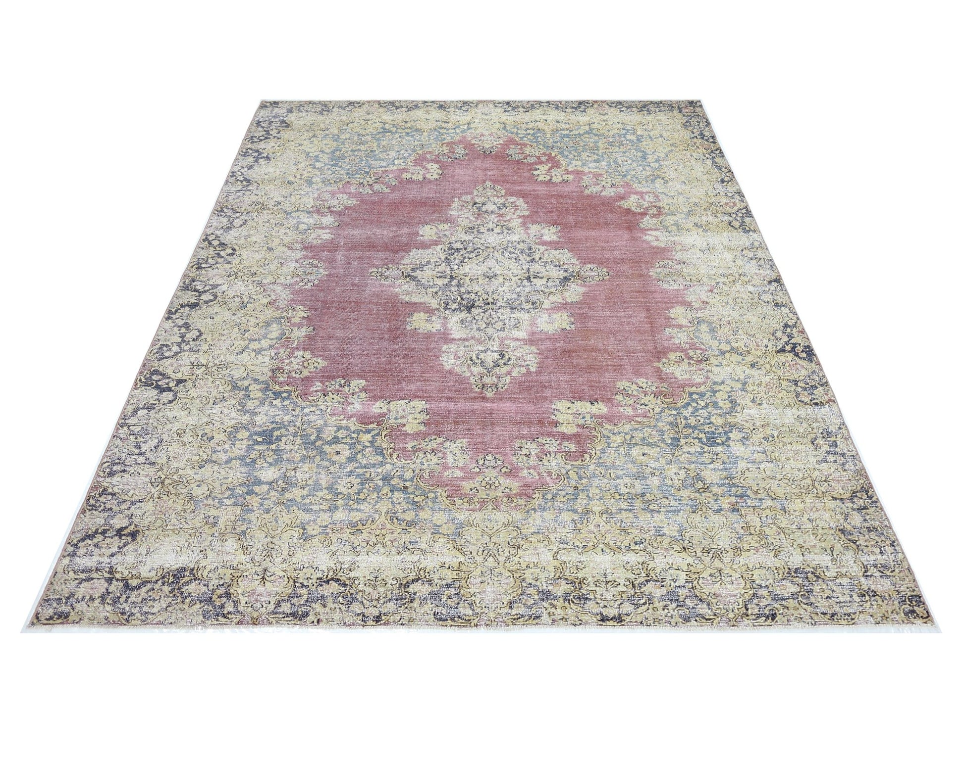 A vintage Persian Kerman rug featuring a central medallion and intricate floral patterns in pink.