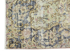 A close-up of a vintage Persian Kerman rug featuring intricate floral patterns in muted tones.