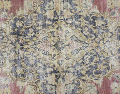 A vintage Persian Kerman rug featuring an intricate floral medallion in muted red, blue, and gold.