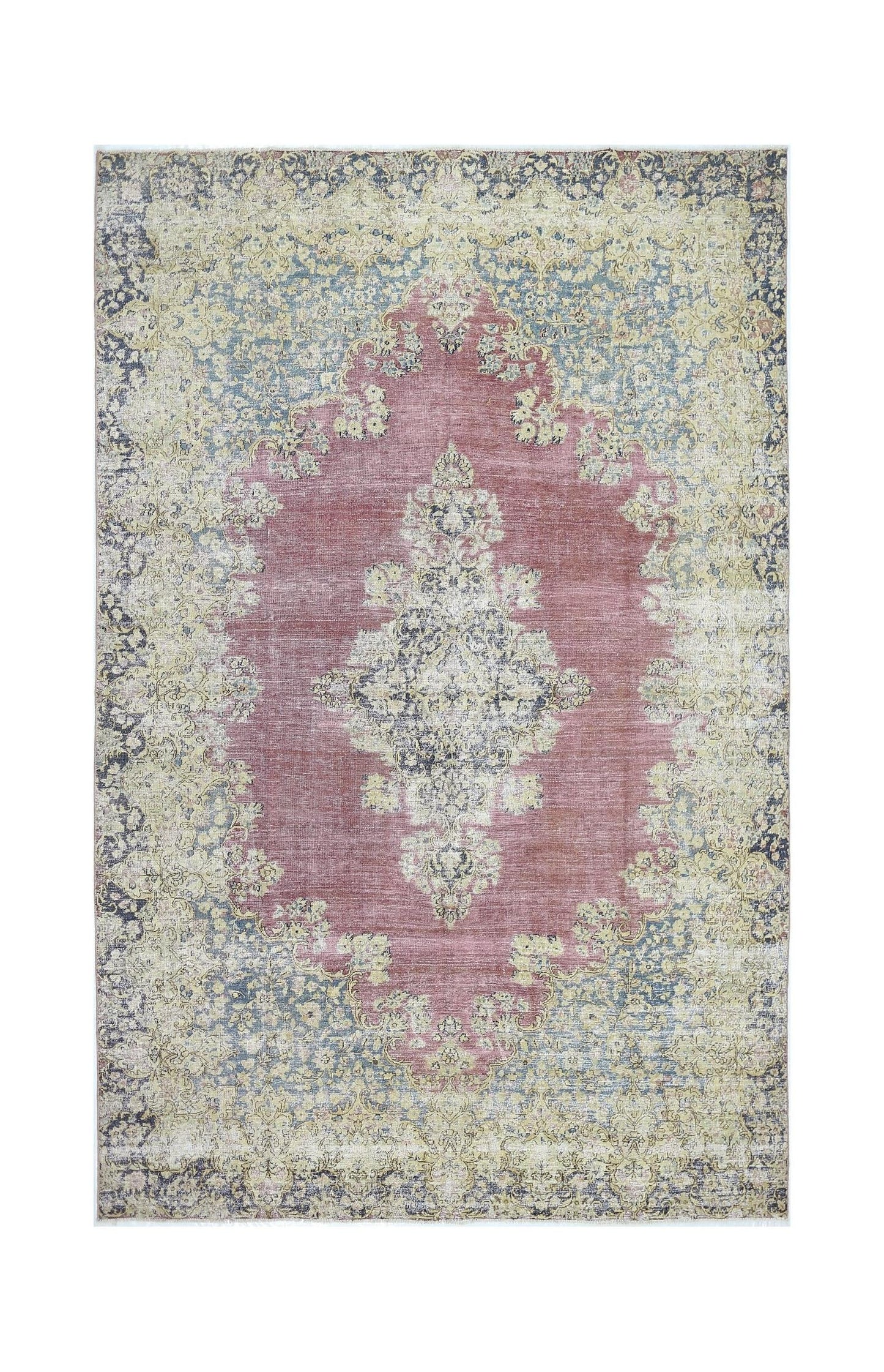 A vintage Persian Kerman rug featuring a central floral medallion in muted pink and blue tones.