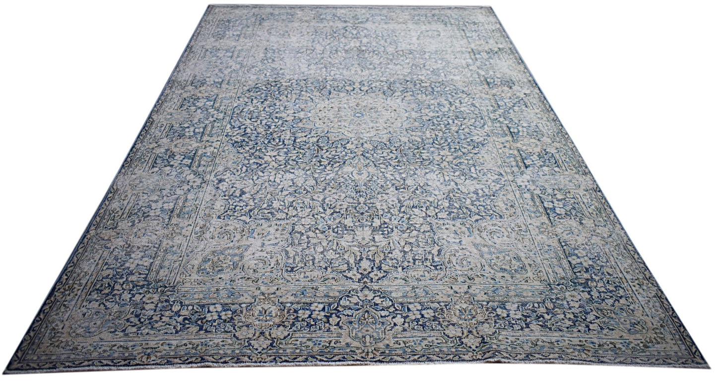 A vintage Persian Kerman rug featuring an intricate blue and cream floral medallion design.