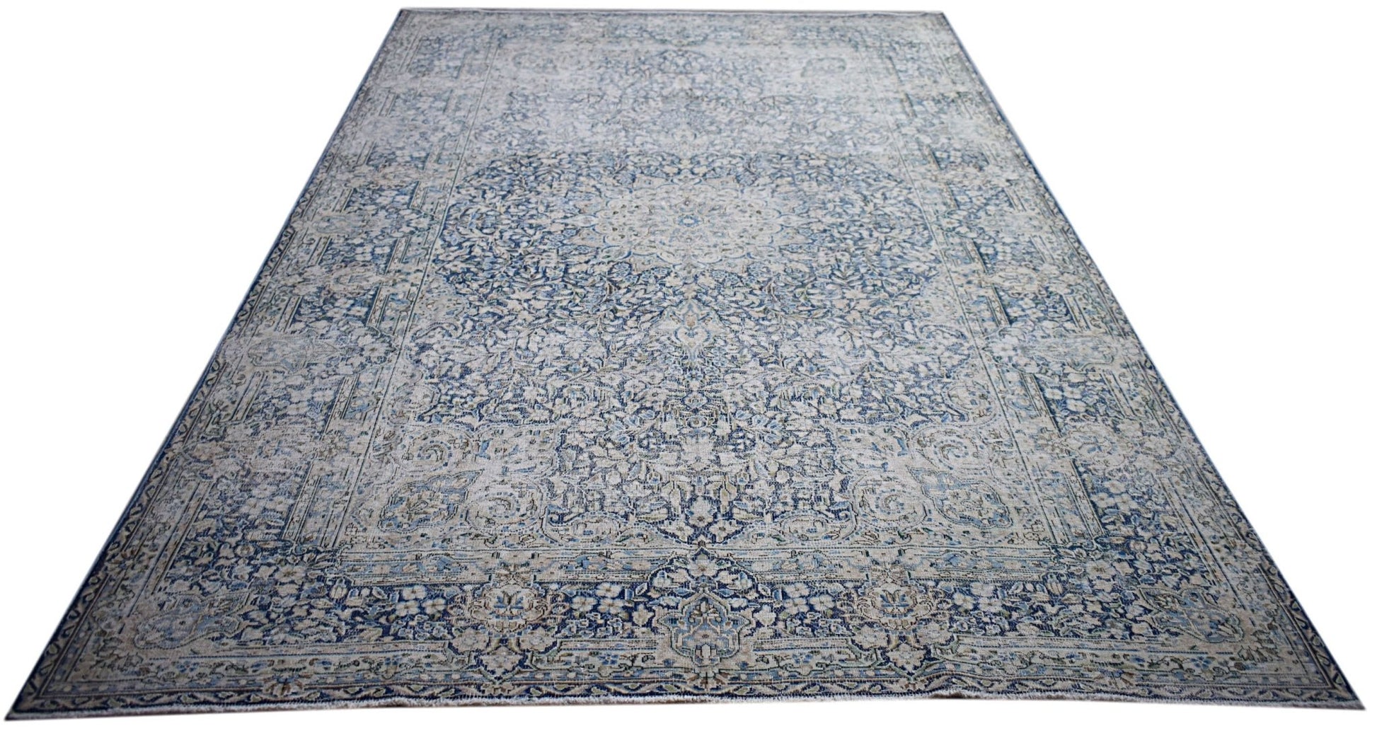 A vintage Persian Kerman rug featuring an intricate blue and cream floral medallion design.