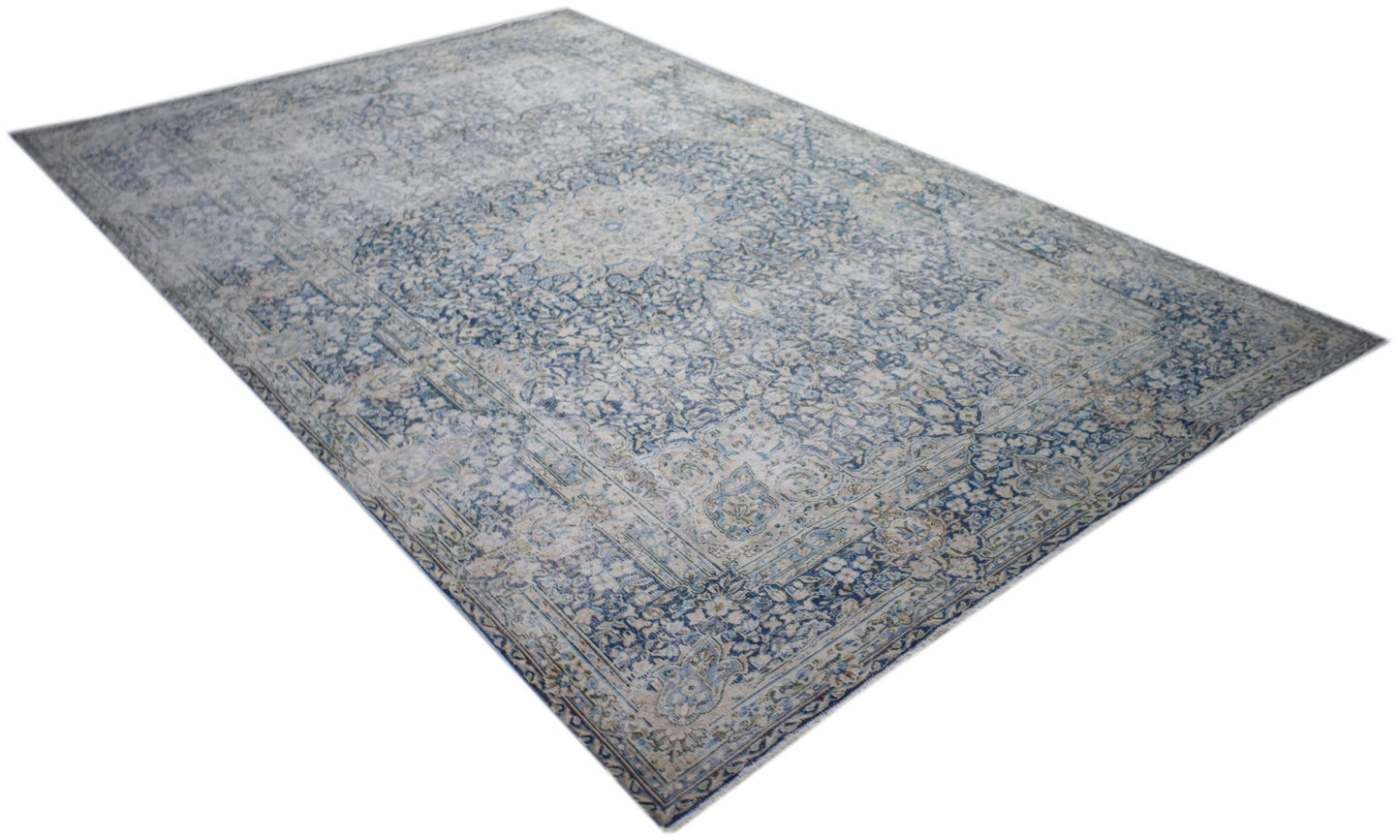 A vintage Persian Kerman rug featuring an intricate blue and cream floral medallion design.