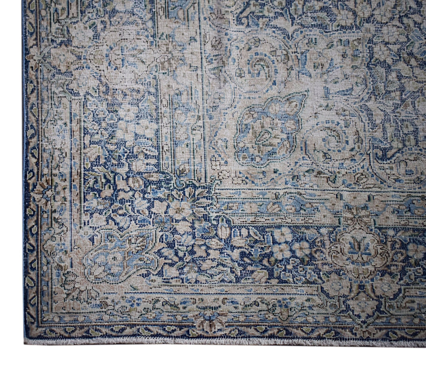 A vintage Persian Kerman rug featuring an intricate blue and beige floral medallion pattern.