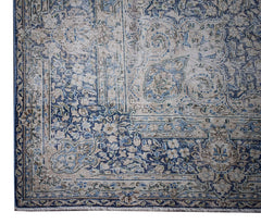 A vintage Persian Kerman rug featuring an intricate blue and beige floral medallion pattern.