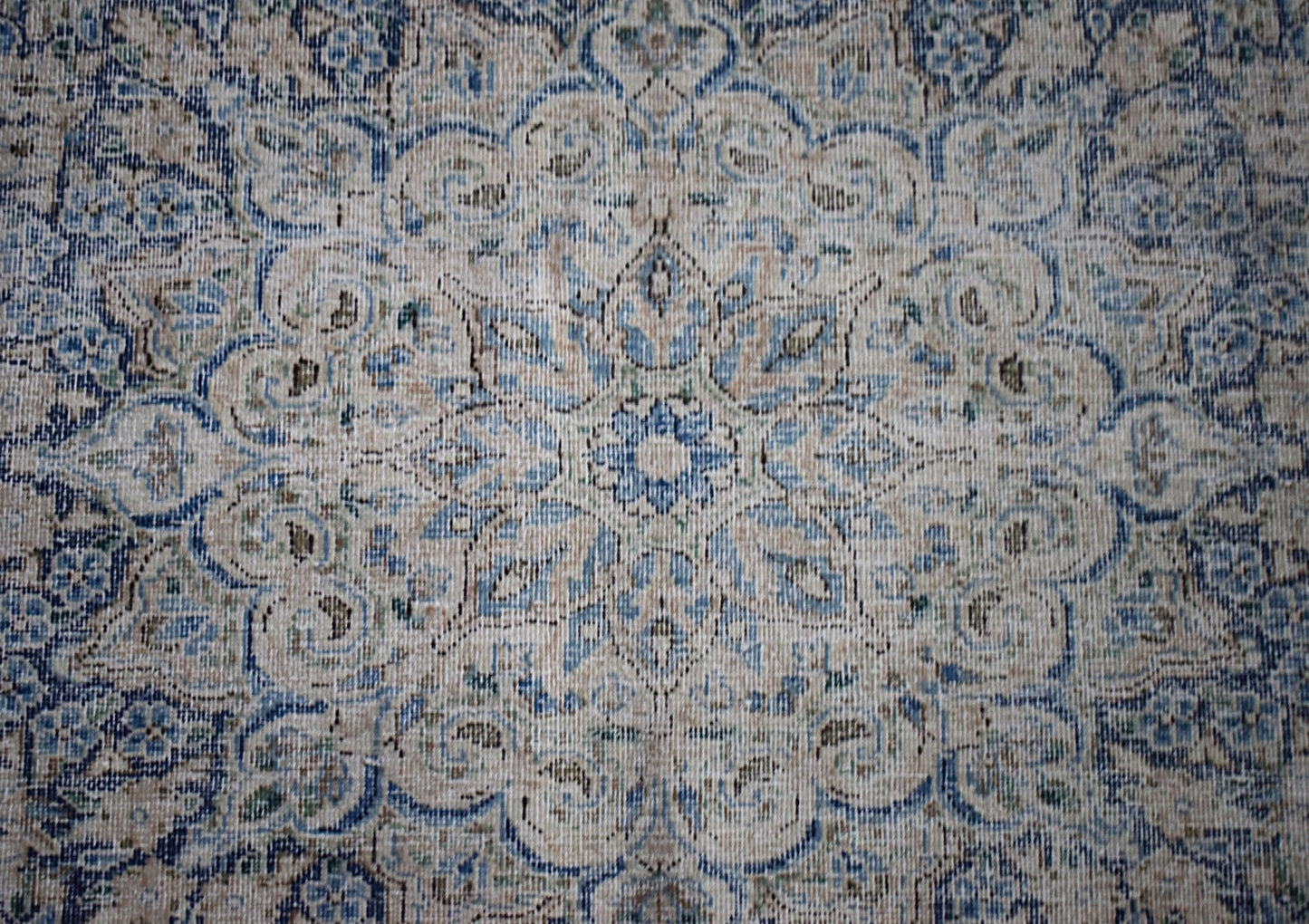 A vintage Persian Kerman rug featuring an intricate blue and beige floral medallion design.