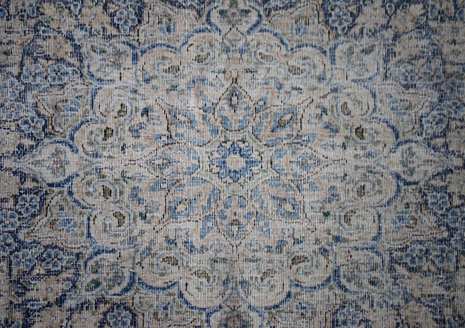 A vintage Persian Kerman rug featuring an intricate blue and beige floral medallion design.