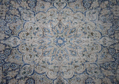 A vintage Persian Kerman rug featuring an intricate blue and beige floral medallion design.