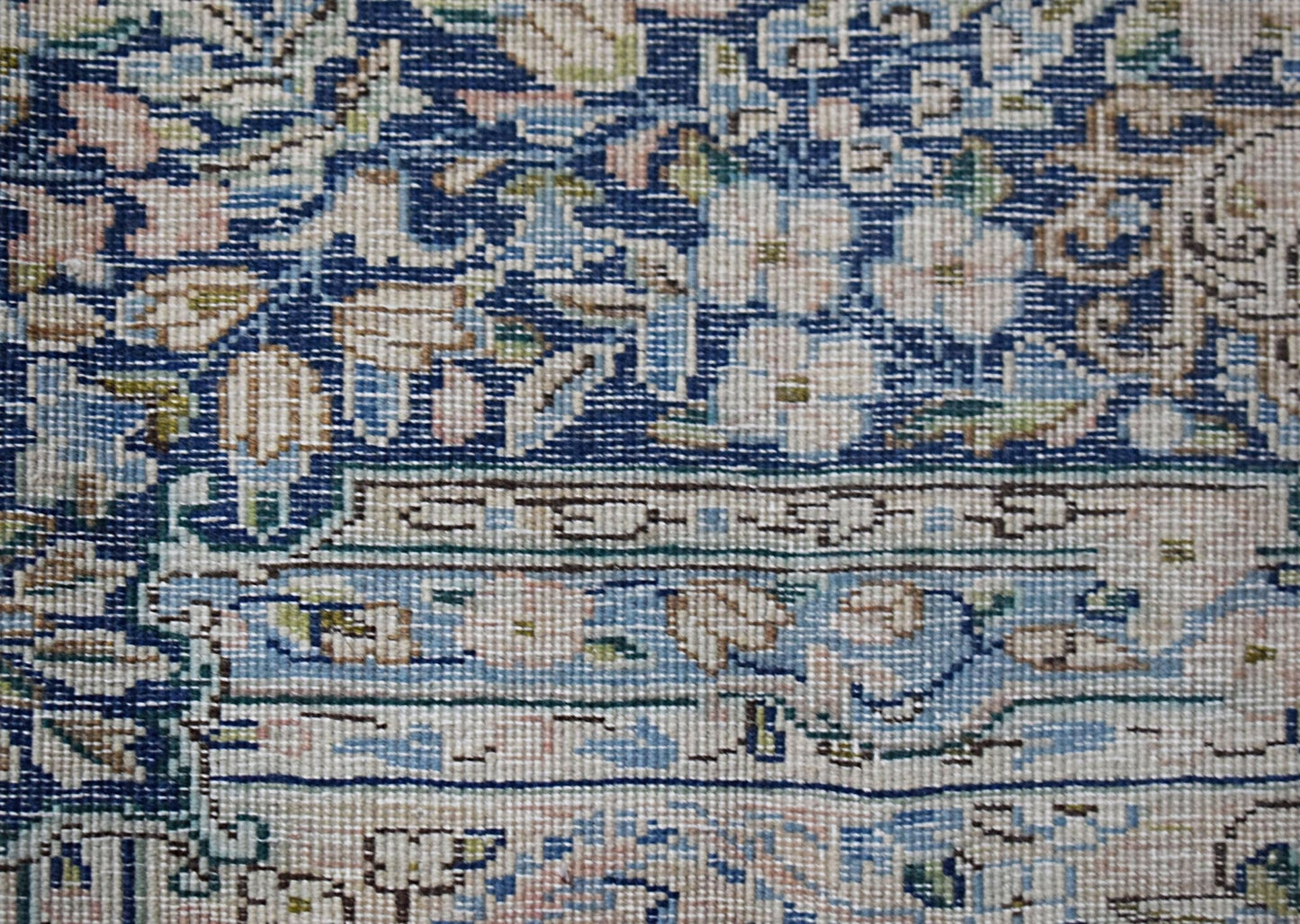 A close-up of a vintage Persian Kerman rug featuring intricate floral patterns in blue and cream.