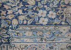 A close-up of a vintage Persian Kerman rug featuring intricate floral patterns in blue and cream.