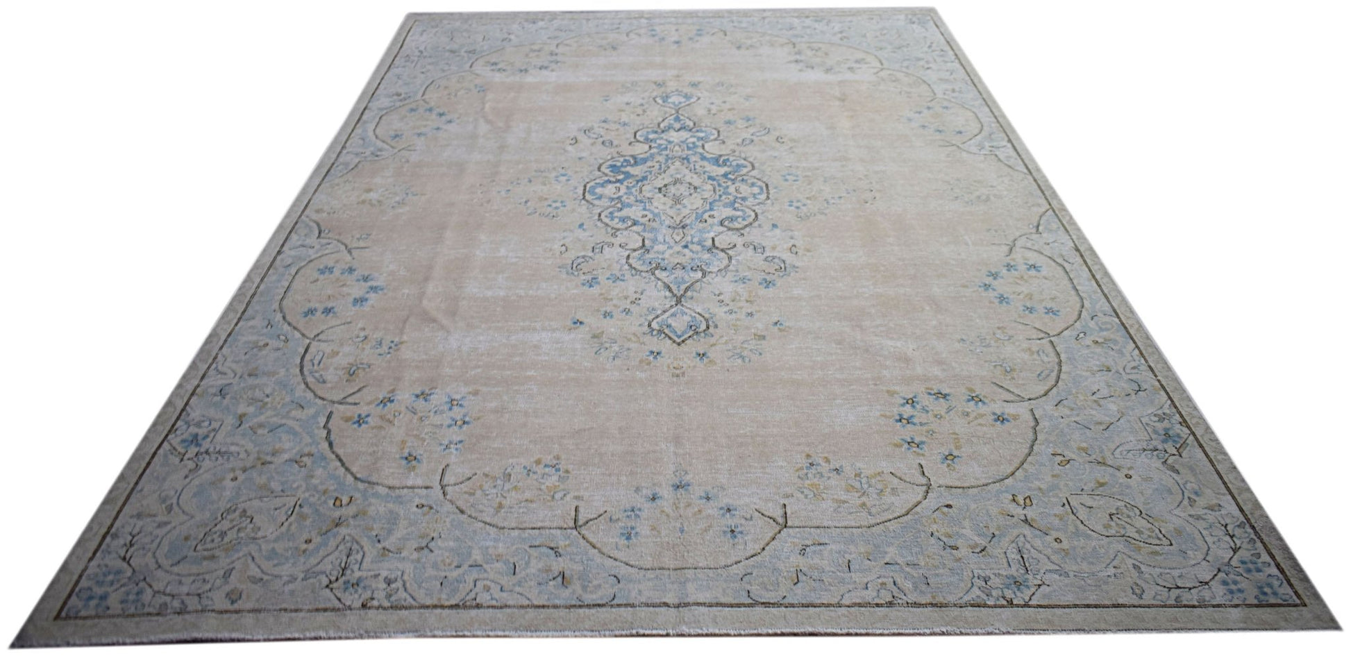 A vintage Persian Kerman rug featuring a central blue medallion on a soft beige floral field.