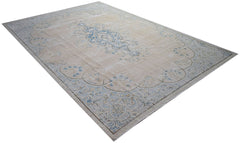 A vintage Persian Kerman rug featuring a central blue medallion on a beige floral field.