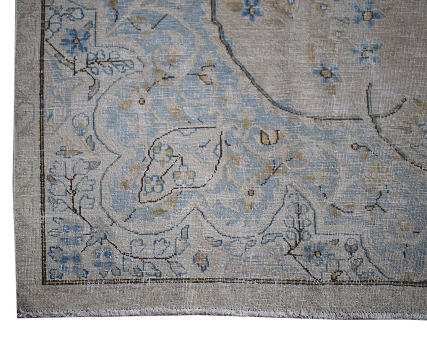 A vintage Persian Kerman rug featuring intricate blue floral patterns on a beige field.