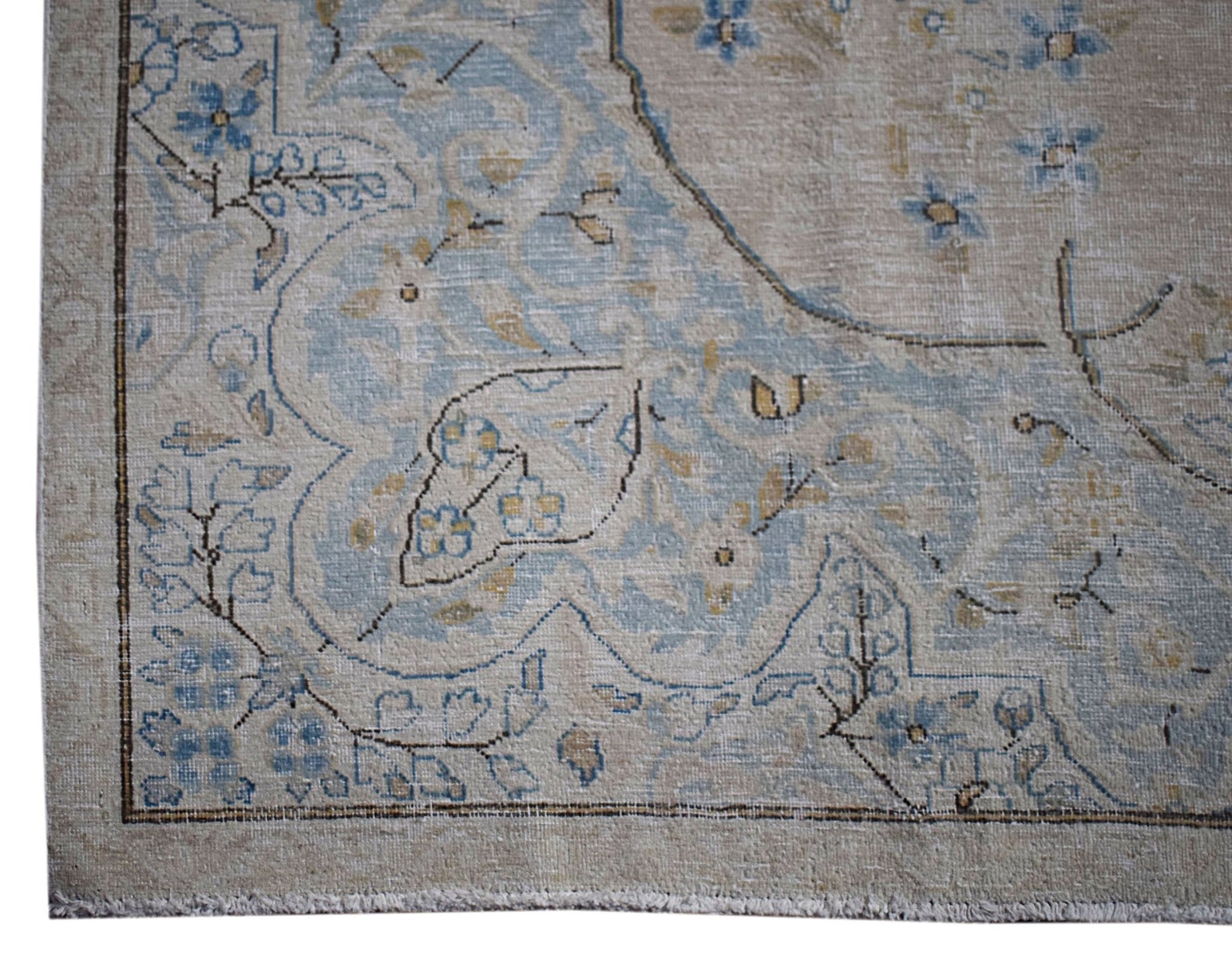 A vintage Persian Kerman rug featuring intricate blue floral patterns on a beige field.