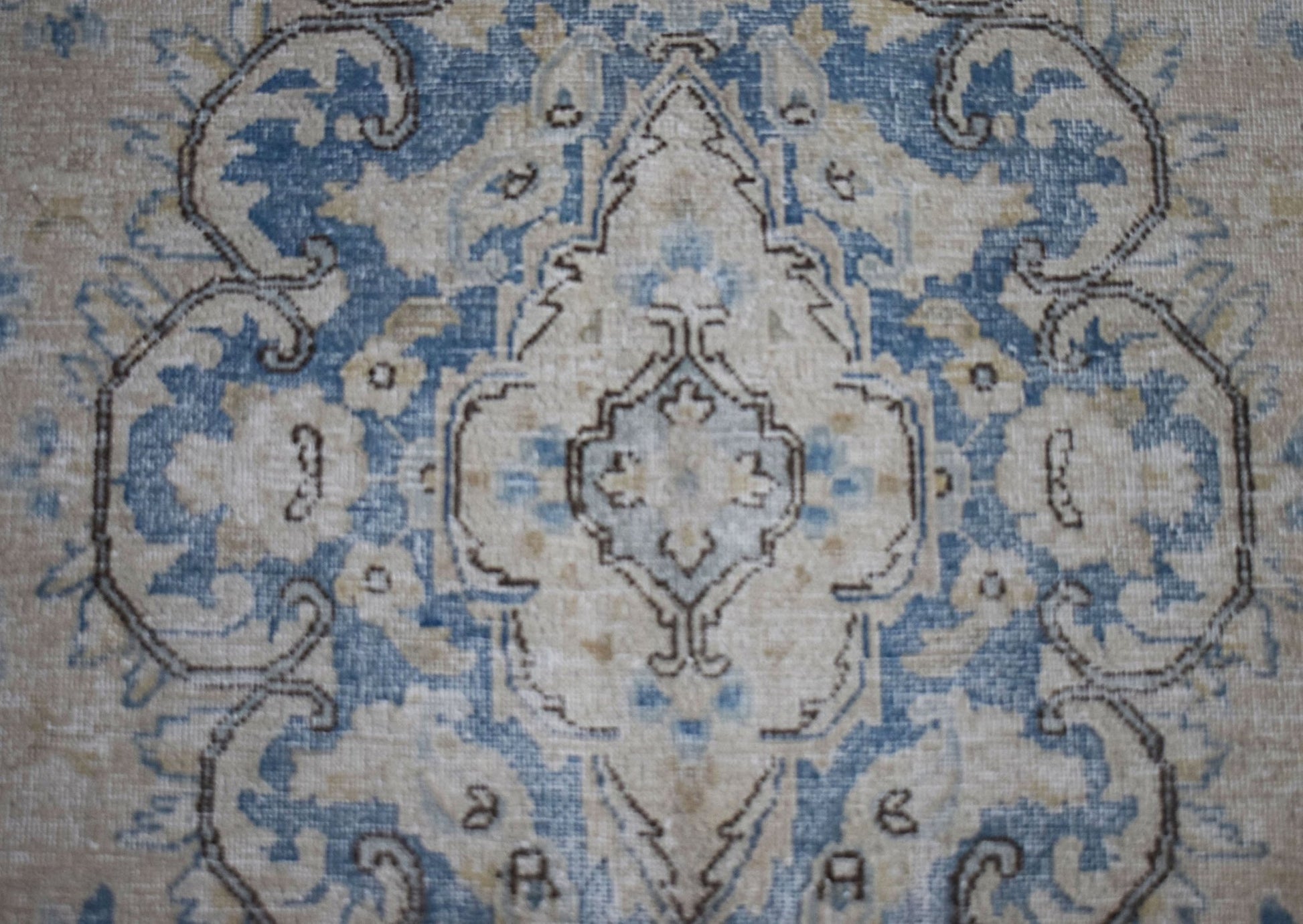 A vintage Persian Kerman rug featuring a central medallion with intricate blue and beige floral motifs.