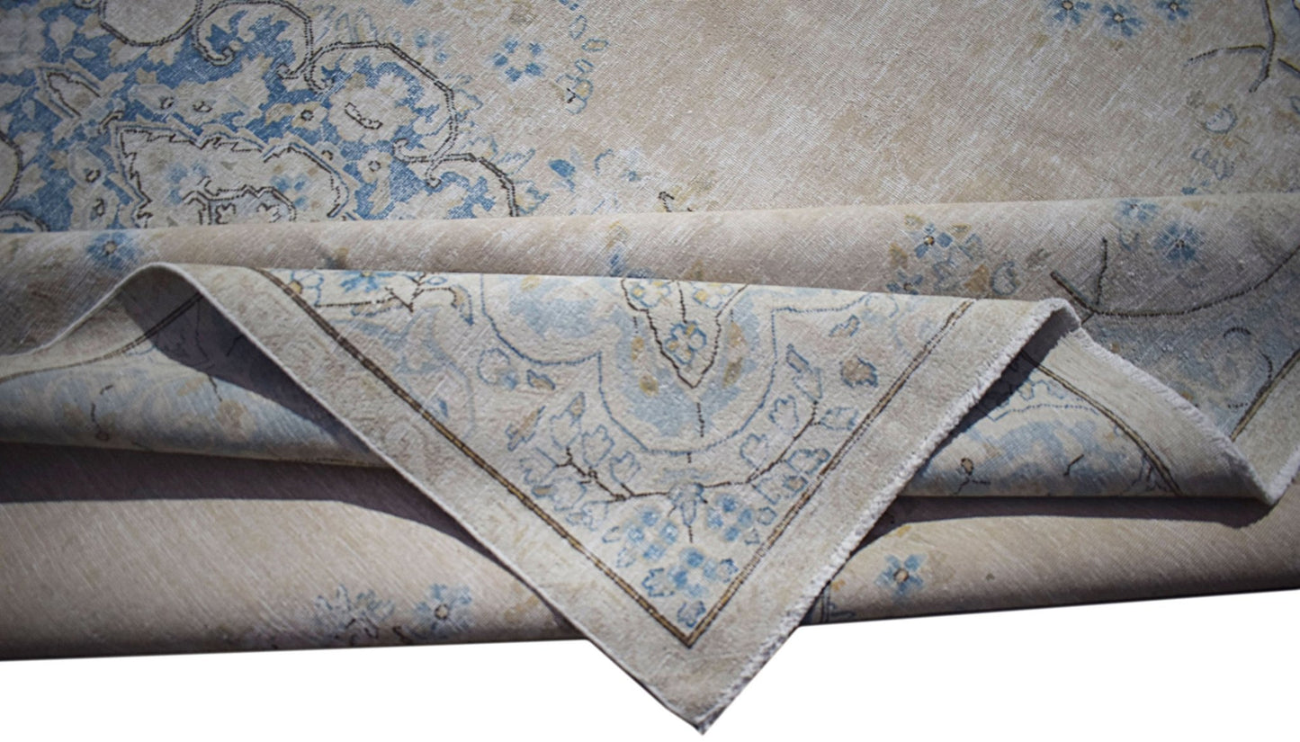 A vintage Persian Kerman rug featuring a light beige field with intricate blue floral patterns.