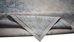A vintage Persian Kerman rug featuring a light beige field with intricate blue floral patterns.