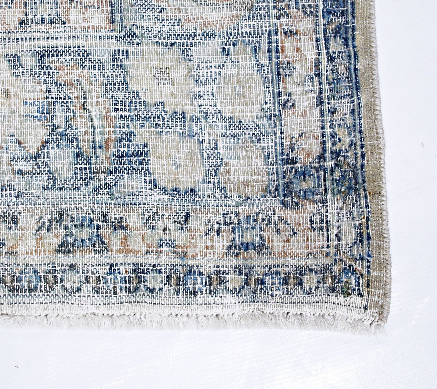 A vintage Persian Kerman rug featuring a faded blue and beige floral medallion pattern.