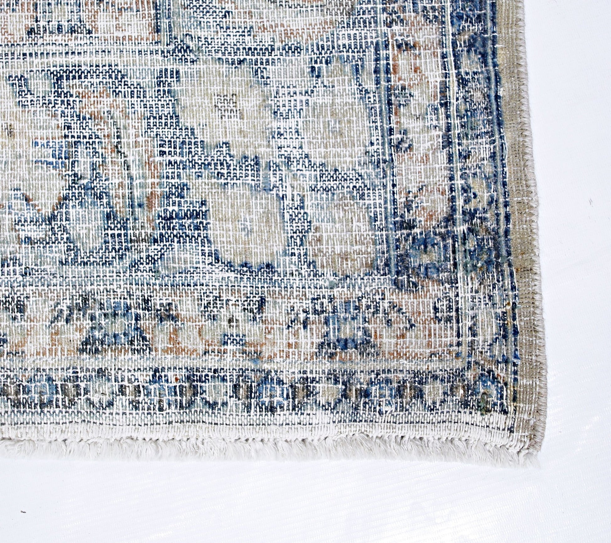 A vintage Persian Kerman rug featuring a faded blue and beige floral medallion pattern.