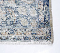 A vintage Persian Kerman rug featuring a faded blue and beige floral medallion pattern.