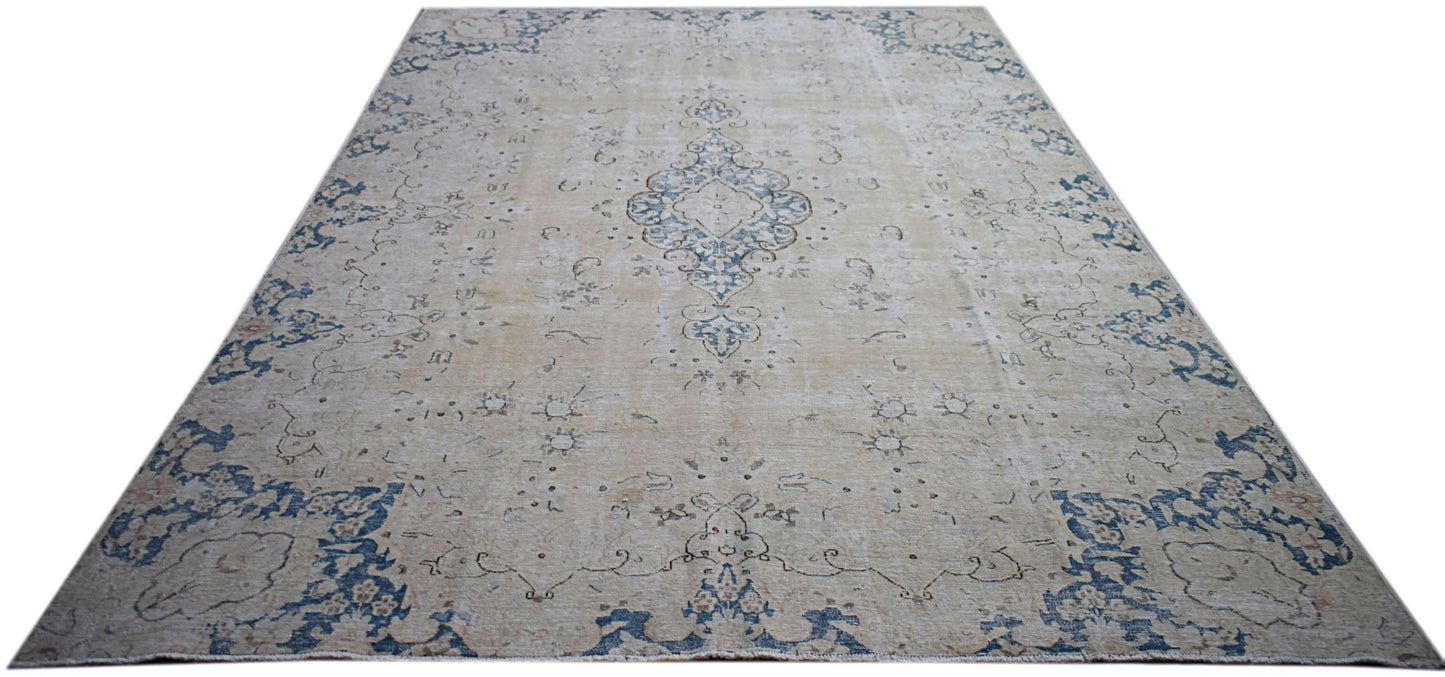 A vintage Persian Kerman rug featuring a central medallion and floral motifs in blue and beige.