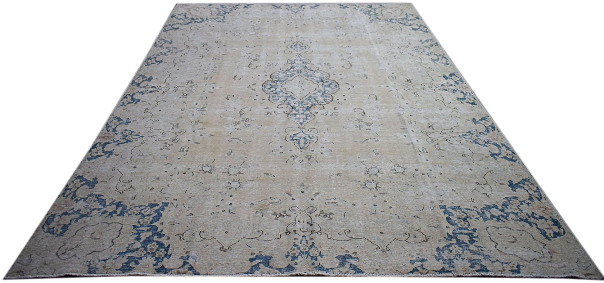 A vintage Persian Kerman rug featuring a central medallion and floral motifs in blue and beige.