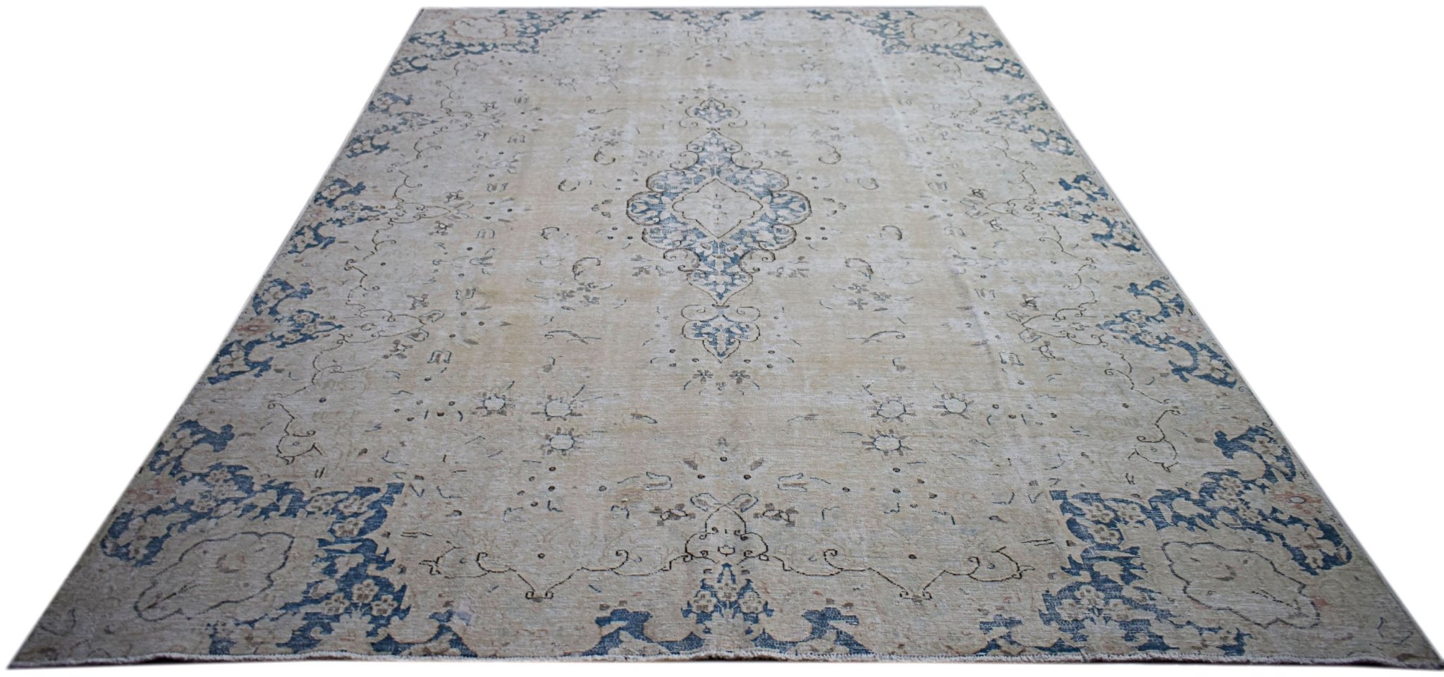 A vintage Persian Kerman rug featuring a central medallion and floral motifs in blue and beige.