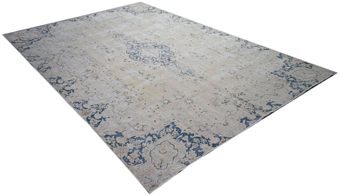 A vintage Persian Kerman rug featuring a central medallion and floral motifs in blue and beige.