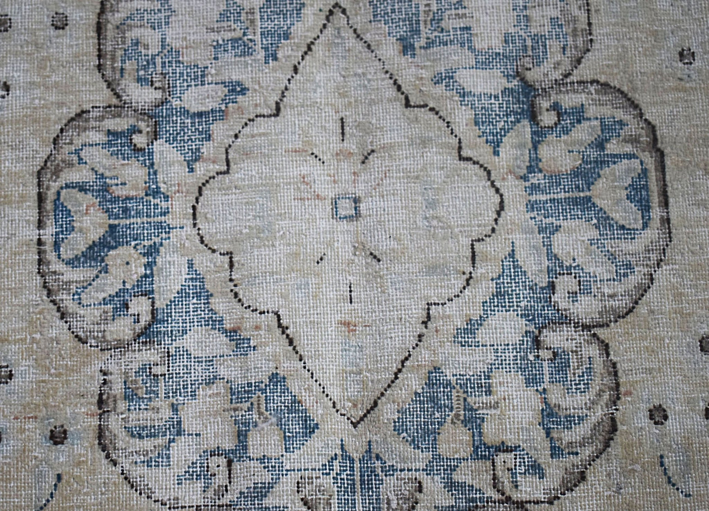 A vintage Persian Kerman rug featuring a central medallion with intricate blue floral patterns.