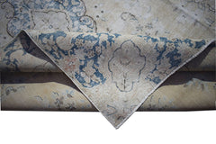 A vintage Persian Kerman rug featuring a blue floral medallion pattern on a beige background.