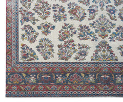 A vintage Persian Kerman rug featuring a cream field with intricate floral motifs and ornate borders.