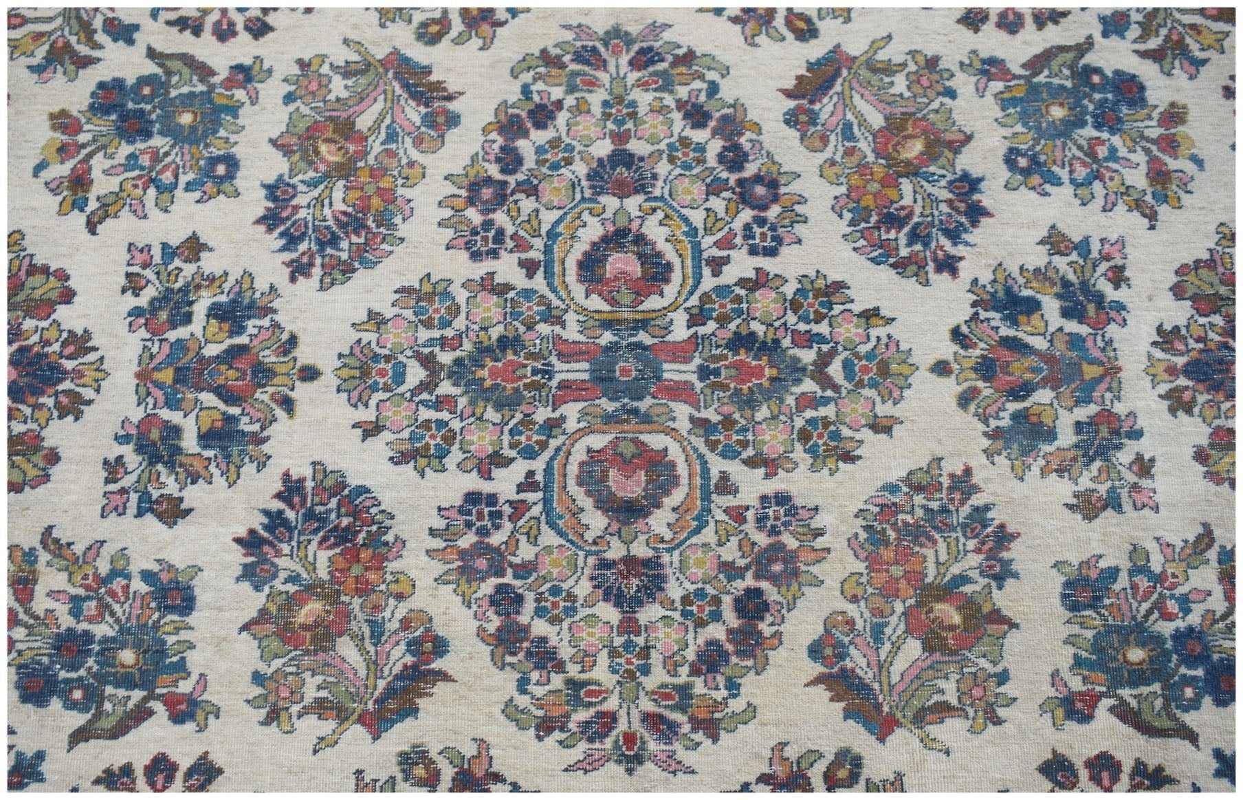 A vintage Persian Kerman rug featuring an intricate floral medallion design on a cream background.