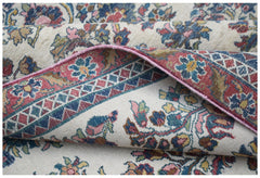 A vintage Persian Kerman rug featuring intricate floral patterns and a folded corner.
