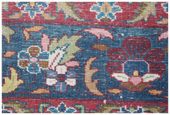 A close-up of a vintage Persian Kerman rug featuring intricate floral patterns in blue and red.