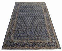 A vintage Persian Kerman rug featuring an intricate blue field with a repeating paisley pattern.