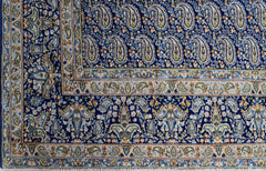 A vintage Persian Kerman rug featuring an intricate blue field with repeating paisley motifs.