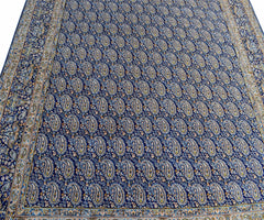 A vintage Persian Kerman rug featuring a dense, repeating paisley pattern in blue and cream tones.